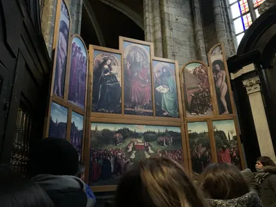 El retablo de La Adoración del Cordero Místico en la catedral de San Bavón de Gante, con visitantes delante