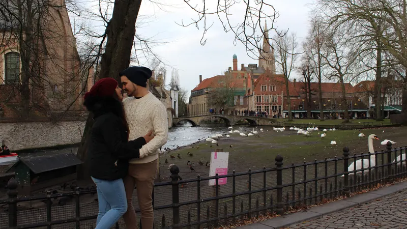 Inma y Álex en el Minnewater de Brujas, con los cisnes y las casas de ladrillo al fondo