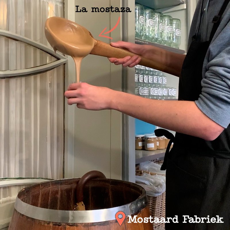 Tendero sirviendo la mostaza directamente desde un barril a un tarro.