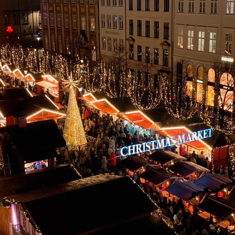 Vista aérea nocturna del mercado de Navidad de Højbro Plads en Copenhague, con la multitud y las luces brillantes.