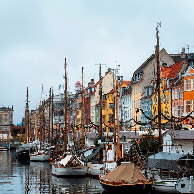 Puestos del mercado de Navidad de Nyhavn junto al canal, con los barcos de madera y las casas de colores de Copenhague.