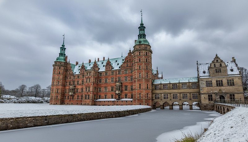 El Castillo de Frederiksborg bajo el manto invernal, con nieve, preparado para la magia de la temporada navideña en su interior.