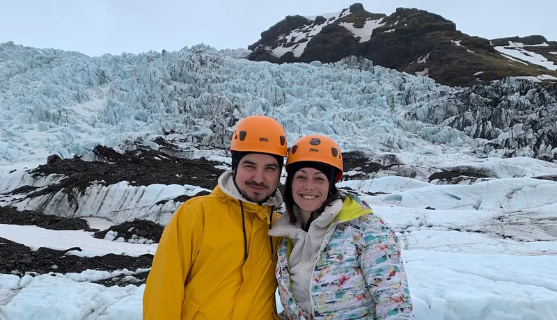Inma y Álex con casco, arnés y crampones frente a la lengua de un glaciar en Skaftafell, Islandia