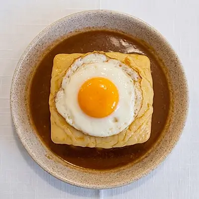 Francesinha, el plato típico de Oporto, con un huevo frito encima y bañada en salsa