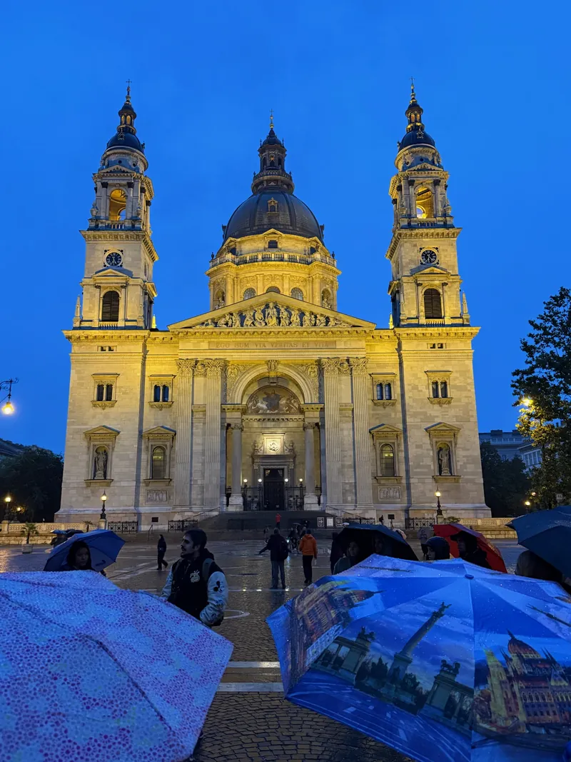 La Basílica de San Esteban de Budapest iluminada al anochecer, con los paraguas del free tour en primer plano