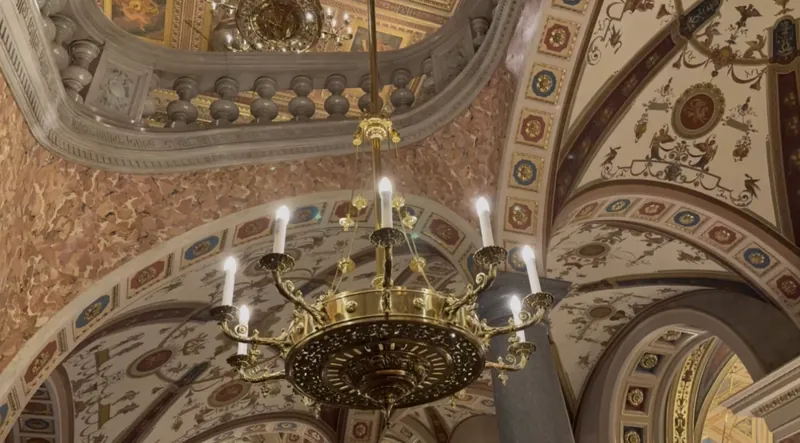 Lámpara de araña dorada y techos abovedados pintados en el interior de la Ópera de Budapest