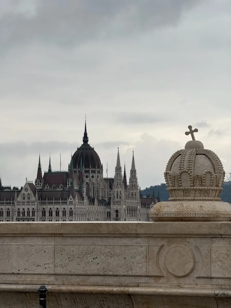 El Parlamento de Budapest visto desde el Puente Margarita, con una corona de piedra del puente en primer plano