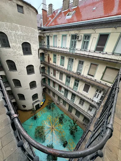 Patio interior del edificio del apartamento de la calle Király de Budapest, con balcones corridos y suelo verde